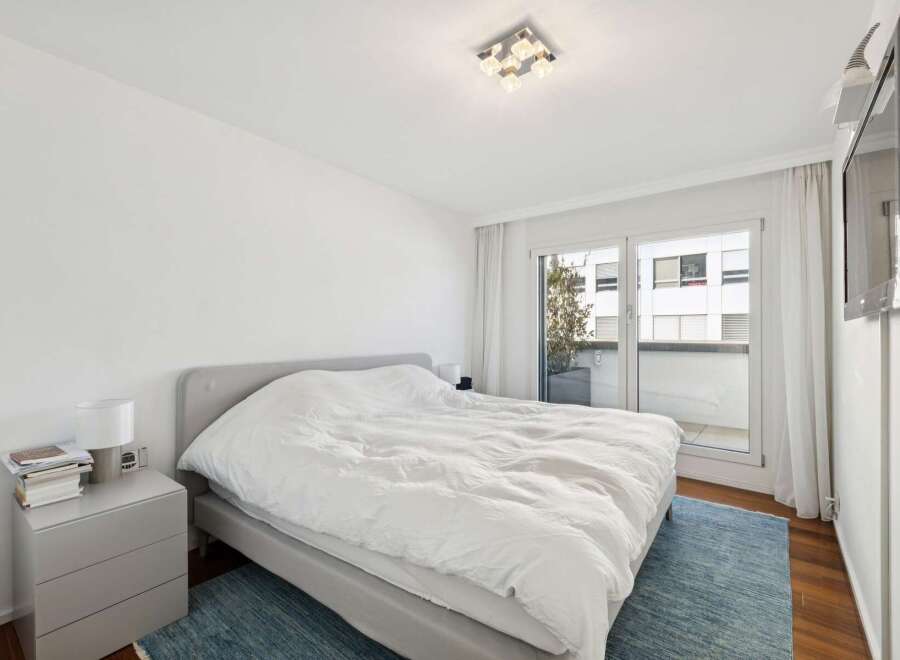 Experience modern comfort in this serene bedroom, featuring a plush king-sized bed with crisp white linens.