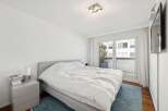 Experience modern comfort in this serene bedroom, featuring a plush king-sized bed with crisp white linens.
