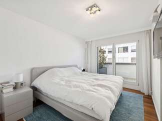 Experience modern comfort in this serene bedroom, featuring a plush king-sized bed with crisp white linens.