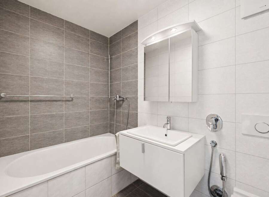 This modern bathroom features a sleek white vanity with a built-in sink, complemented by a large mirrored medicine cabinet above.