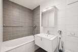 This modern bathroom features a sleek white vanity with a built-in sink, complemented by a large mirrored medicine cabinet above.