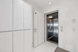 Step into modern convenience with this spacious entryway featuring a sleek white wardrobe and direct access to a private elevator.
