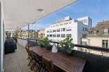 Enjoy outdoor living on this spacious balcony, perfect for al fresco dining with a large wooden table and chairs.