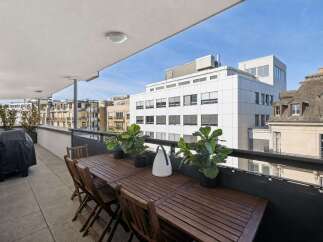 Enjoy outdoor living on this spacious balcony, perfect for al fresco dining with a large wooden table and chairs.