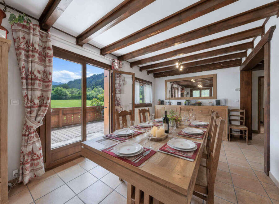Experience rustic charm in this dining room, featuring exposed wooden beams and a large wooden table set for a meal.