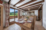 Experience rustic charm in this dining room, featuring exposed wooden beams and a large wooden table set for a meal.