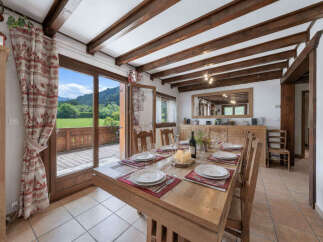 Experience rustic charm in this dining room, featuring exposed wooden beams and a large wooden table set for a meal.