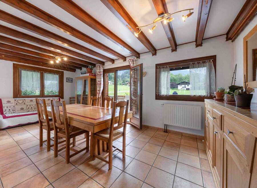 Experience cozy living in this charming dining area, featuring exposed wooden beams and a rustic wooden dining set perfect for family meals.