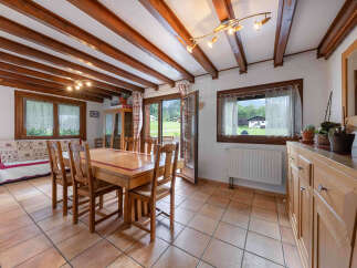 Experience cozy living in this charming dining area, featuring exposed wooden beams and a rustic wooden dining set perfect for family meals.