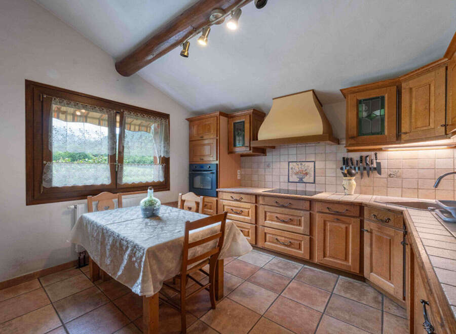 This charming kitchen features rustic wooden cabinetry and a cozy dining nook with a window overlooking the outdoors.