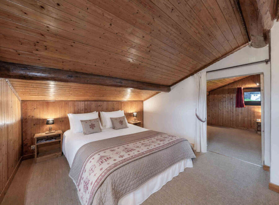 Experience rustic charm in this cozy bedroom featuring a beautifully crafted wooden ceiling and walls, creating a warm and inviting atmosphere.