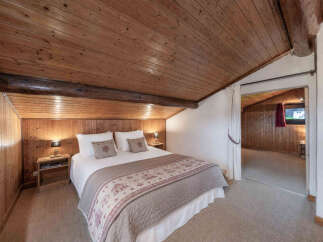 Experience rustic charm in this cozy bedroom featuring a beautifully crafted wooden ceiling and walls, creating a warm and inviting atmosphere.