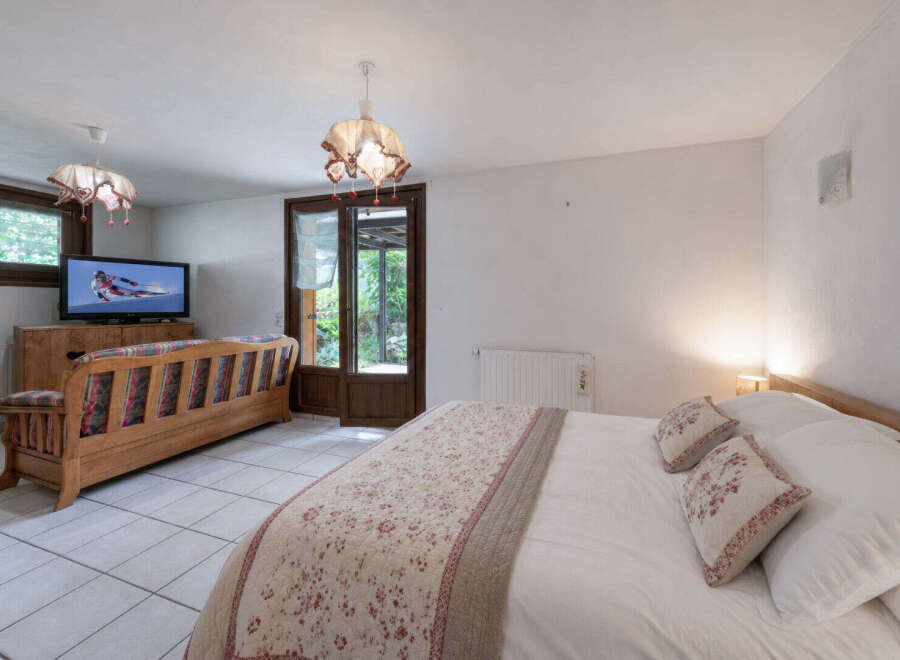 This charming bedroom features a comfortable queen-size bed adorned with decorative pillows and a floral-patterned bedspread.