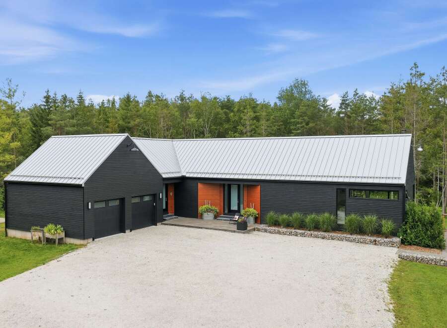 Discover modern living in this striking black home featuring a sleek metal roof and warm wood accents.