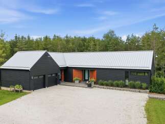 Discover modern living in this striking black home featuring a sleek metal roof and warm wood accents.