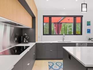 Experience modern luxury in this stunning kitchen, featuring sleek dark gray cabinetry complemented by warm wood accents.