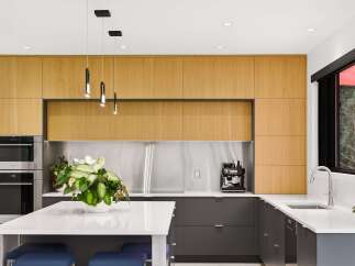 Experience modern luxury in this stunning kitchen, featuring sleek wood cabinetry and a professional-grade stainless steel backsplash.