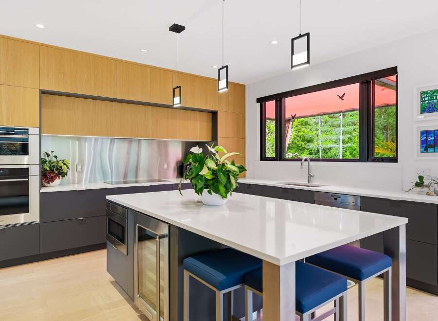 Experience modern luxury in this stunning kitchen, featuring sleek wood cabinetry and a spacious quartz island perfect for entertaining.