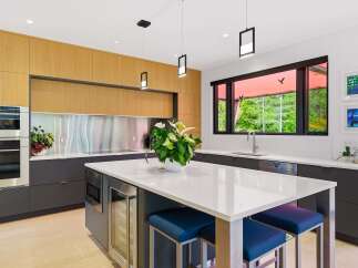 Experience modern luxury in this stunning kitchen, featuring sleek wood cabinetry and a spacious quartz island perfect for entertaining.