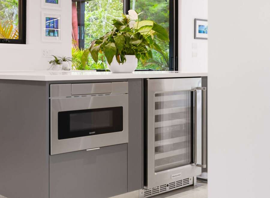 This modern kitchen features a sleek built-in Sharp microwave and a stainless steel KitchenAid wine cooler, perfect for entertaining.