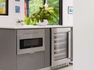This modern kitchen features a sleek built-in Sharp microwave and a stainless steel KitchenAid wine cooler, perfect for entertaining.