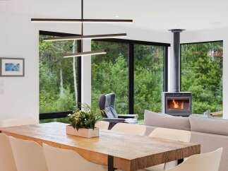 Experience modern living with this stunning open-concept space, featuring a large wooden dining table perfect for gatherings and a cozy fireplace for warm evenings.