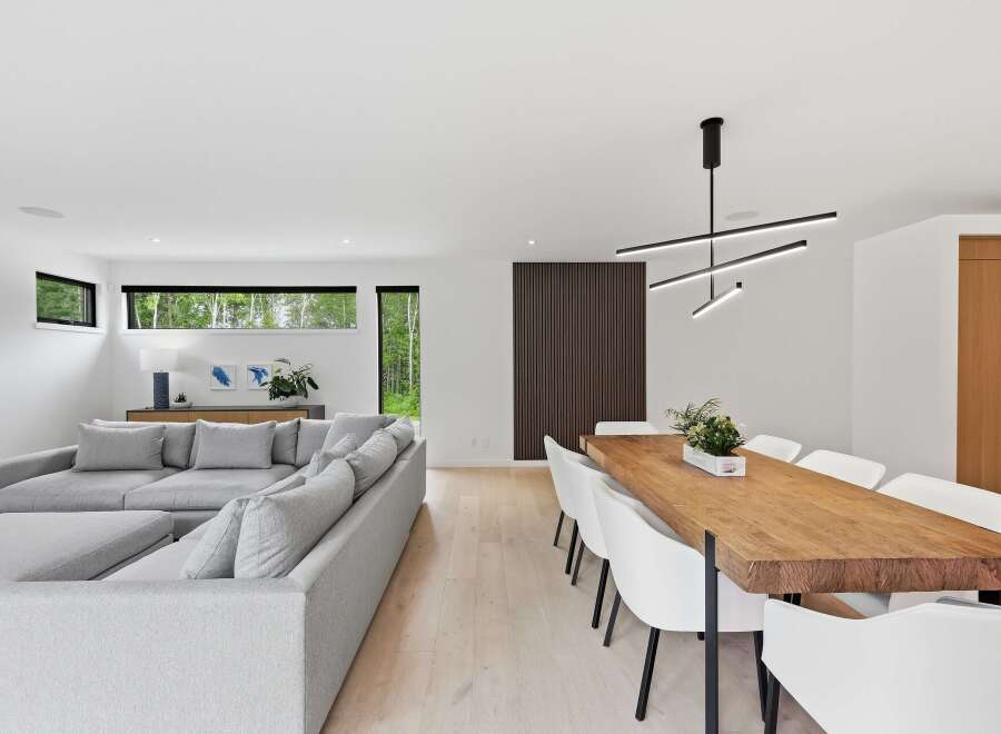Experience modern living in this open-concept space, featuring a spacious sectional sofa perfect for relaxation and a stunning live-edge dining table that seats eight.