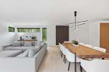 Experience modern living in this open-concept space, featuring a spacious sectional sofa perfect for relaxation and a stunning live-edge dining table that seats eight.