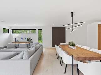 Experience modern living in this open-concept space, featuring a spacious sectional sofa perfect for relaxation and a stunning live-edge dining table that seats eight.