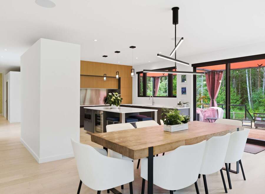 Experience modern living in this stunning open-concept dining and kitchen area, featuring a live-edge wood dining table with sleek white chairs.