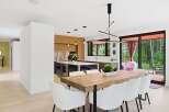 Experience modern living in this stunning open-concept dining and kitchen area, featuring a live-edge wood dining table with sleek white chairs.