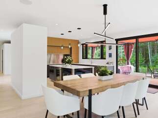 Experience modern living in this stunning open-concept dining and kitchen area, featuring a live-edge wood dining table with sleek white chairs.
