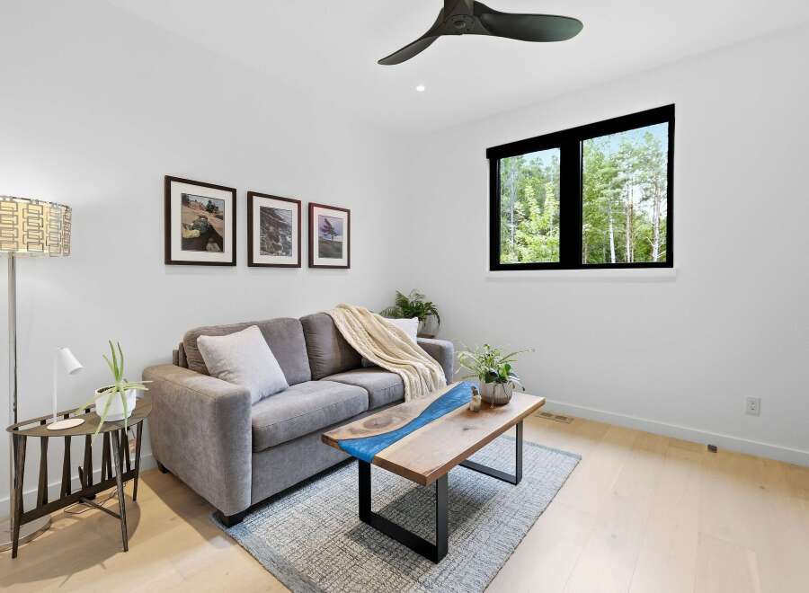 Experience modern living in this bright and airy living room, featuring a plush grey sofa adorned with a cozy knit throw and accent pillows.