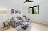 Experience modern living in this bright and airy living room, featuring a plush grey sofa adorned with a cozy knit throw and accent pillows.