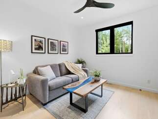 Experience modern living in this bright and airy living room, featuring a plush grey sofa adorned with a cozy knit throw and accent pillows.