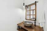 This modern bathroom features a unique stone vessel sink atop a rustic live-edge wood vanity.