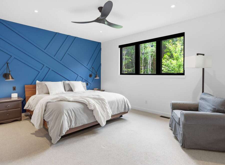 Experience luxury in this stunning bedroom featuring a striking blue accent wall with geometric paneling.