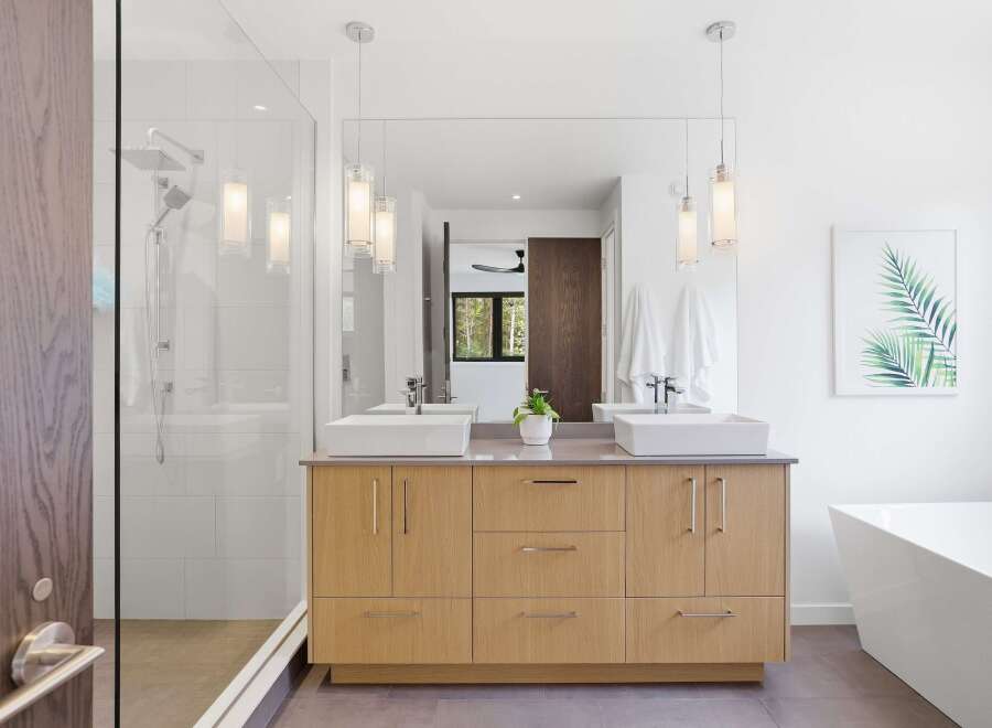 Experience modern luxury in this stunning bathroom featuring a double vanity with vessel sinks and sleek wood cabinetry.