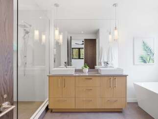 Experience modern luxury in this stunning bathroom featuring a double vanity with vessel sinks and sleek wood cabinetry.