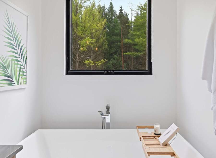 Experience tranquility in this modern bathroom, featuring a deep soaking tub with a sleek chrome faucet.