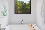 Experience tranquility in this modern bathroom, featuring a deep soaking tub with a sleek chrome faucet.