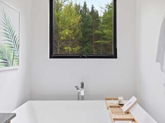 Experience tranquility in this modern bathroom, featuring a deep soaking tub with a sleek chrome faucet.
