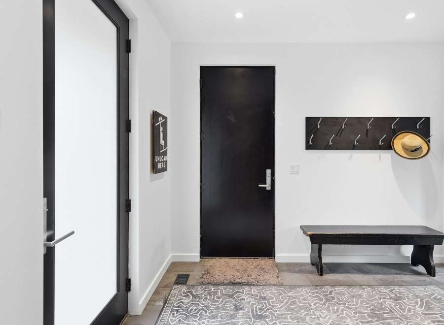 Step into this modern entryway featuring a sleek black door and a convenient coat rack with a stylish straw hat.