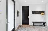 Step into this modern entryway featuring a sleek black door and a convenient coat rack with a stylish straw hat.