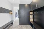 This modern entryway features a sleek dark wood built-in cabinet system with ample storage and convenient hooks for coats and accessories.