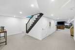 Discover this beautifully finished basement featuring a modern staircase with black railings and a bright, open-concept living area.