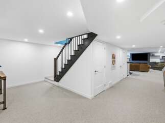 Discover this beautifully finished basement featuring a modern staircase with black railings and a bright, open-concept living area.