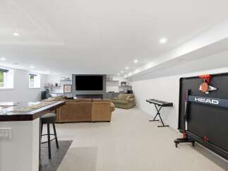 This finished basement offers a versatile entertainment space, complete with a large sectional sofa facing a modern fireplace and entertainment center.