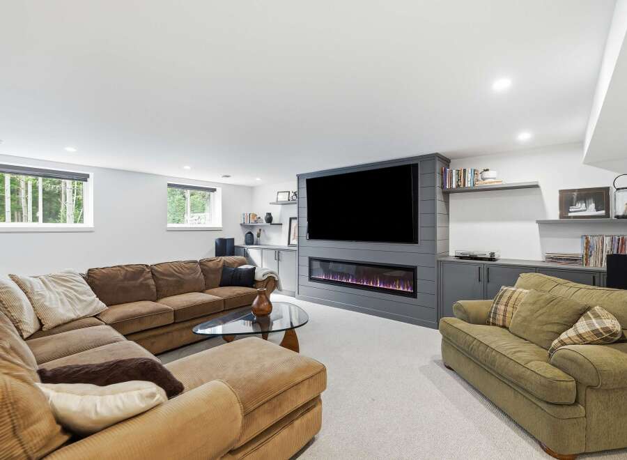 Experience ultimate relaxation in this modern basement living room, featuring a plush sectional sofa and a cozy armchair perfect for unwinding.