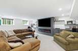 Experience ultimate relaxation in this modern basement living room, featuring a plush sectional sofa and a cozy armchair perfect for unwinding.